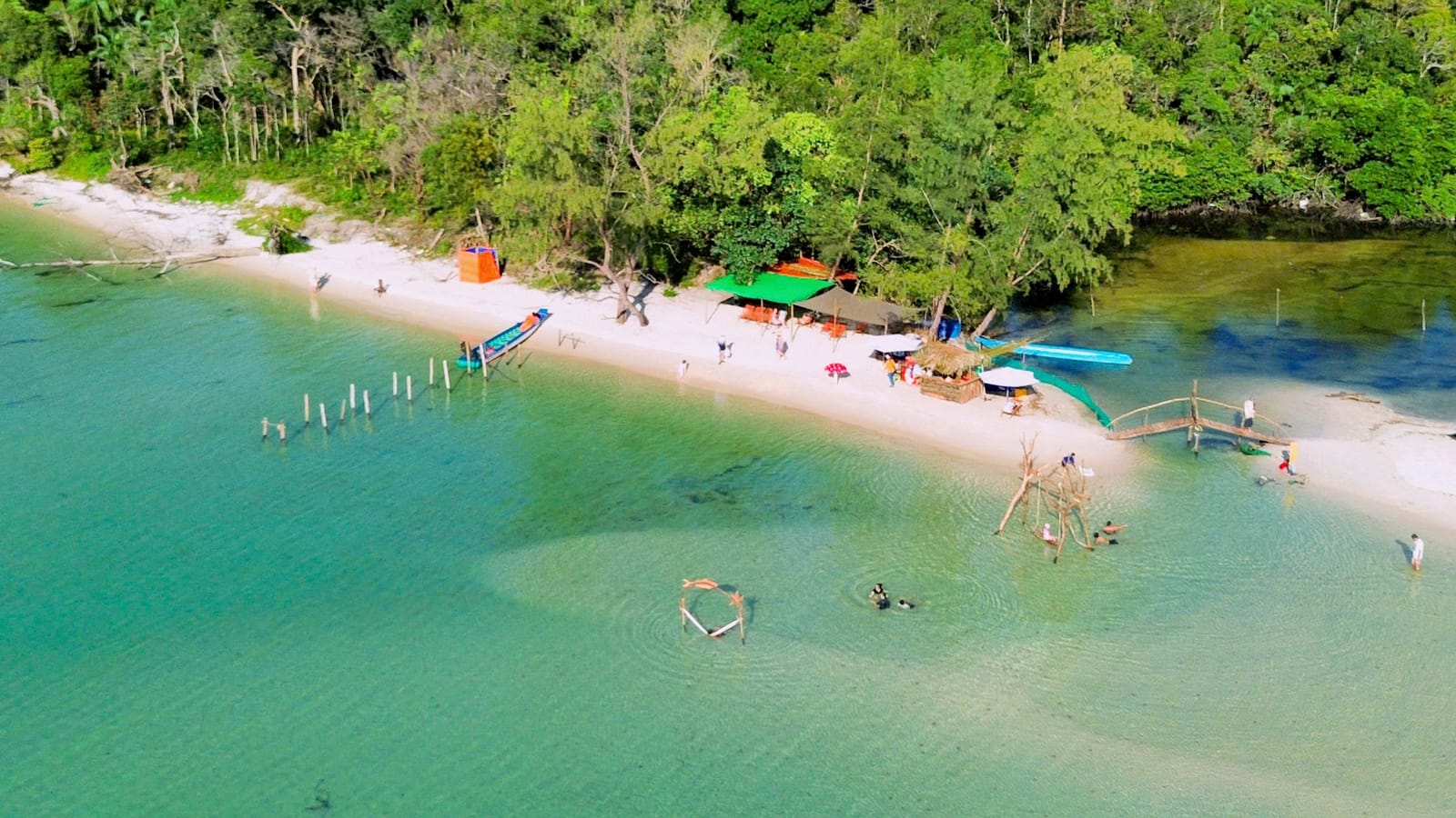 Ham Rong’s shallows with beach huts along the shore and the tree line behind