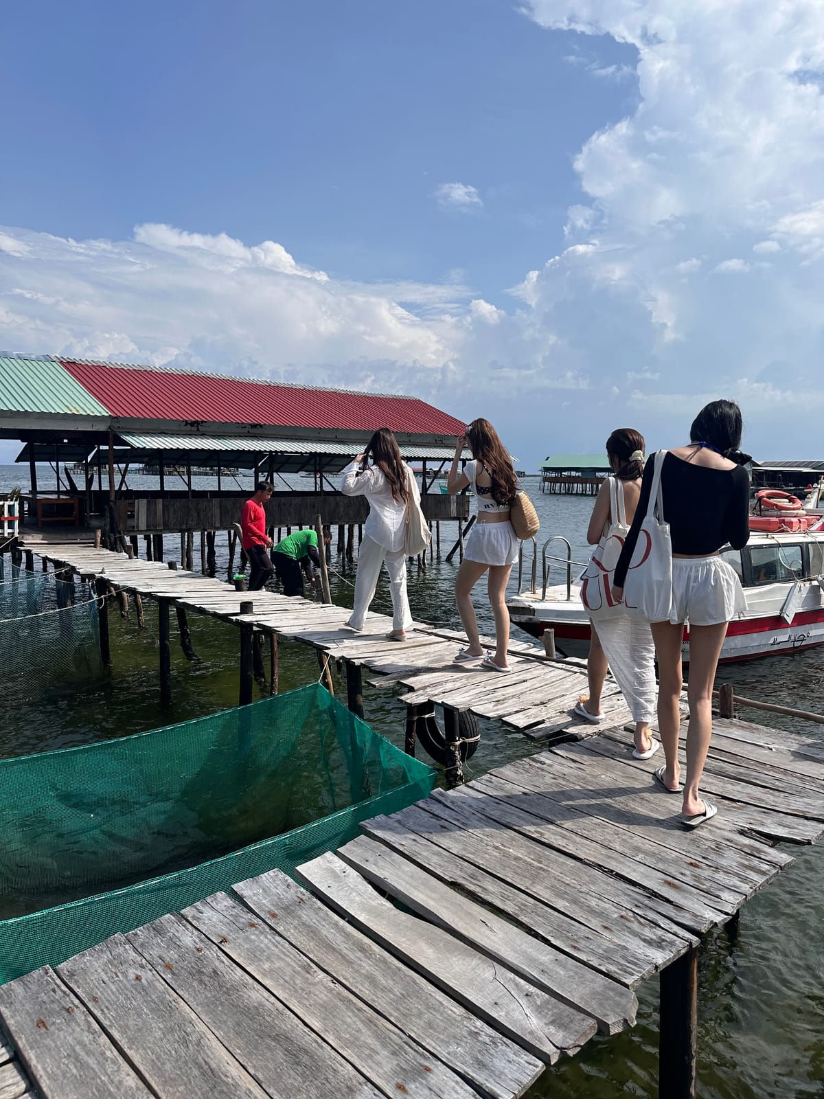 Guests walking the wooden pier to the raft, a speedboat moored by the pens